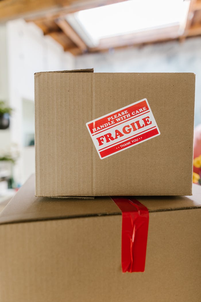 Close-up of cardboard boxes stacked with fragile care label in an indoor setting.